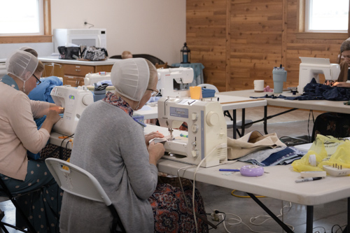 Four women face each other as they work at their sewing machines.
