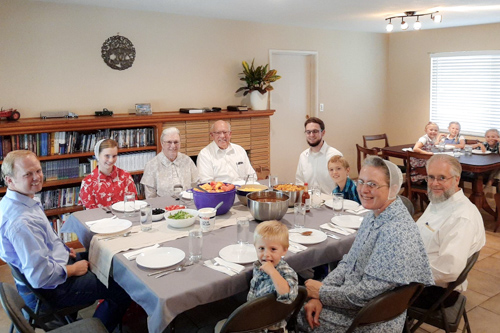 A small group of family and friends smile for the camera as they get ready to eat a meal.