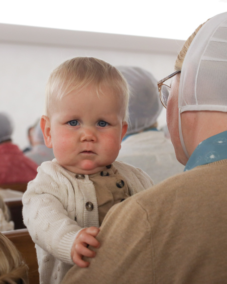 A curious baby looks over his mother's shoulder during a church service.