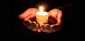 Hands holding a lit candle